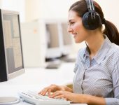 woman with headphones typing on computer