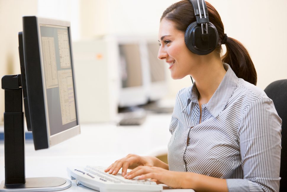 woman with headphones typing on computer